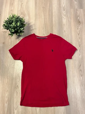 Röd U.S Polo ASSN. T-shirt  - Säljer nu en Röd U.S Polo ASSN. T-shirt i fint skick. Tröjan är i storlek M. Ända defekt som finns är ett super litet hål bak vid naken. Annars jätte fint skick. Skickar som alltid inom 24 timmar  Priset är inte hugget i sten