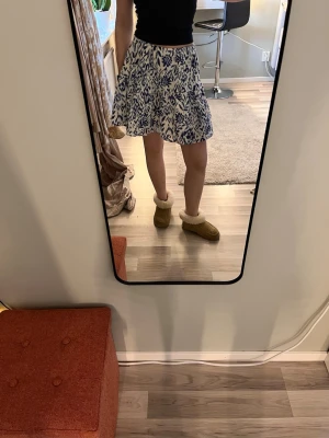 Vit och blå kortkjol med blommigt mönster - Säljer en söt blå vit blommig kjol i tunt tyg så den är sval och skön till sommaren. Pris kan diskuteras💕