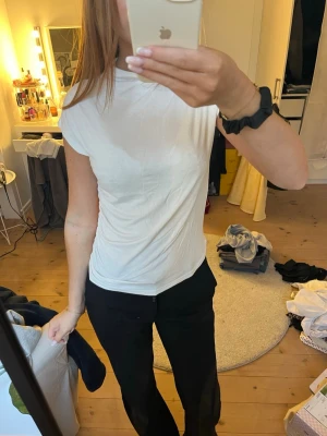 Vit basic t-shirt i bomull - En enkel vit t-shirt med rund hals och korta ärmar. Modellen är figurnära och passar perfekt till alla typer av outfits. Tillverkad i mjuk bomull som känns skön mot huden. Perfekt för dig som gillar en clean och stilren look.
