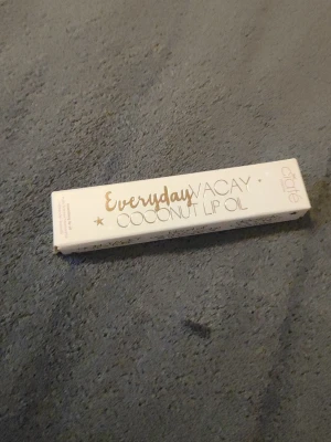 Everyday Vacay Coconut Lip Oil - Fräsch läppolja från Ciaté i varianten Everyday Vacay Coconut Lip Oil. Kommer i en vit, avlång förpackning med guldtext. Ger en mjuk och återfuktande känsla till läpparna med en hint av kokosdoft. Perfekt för dig som vill ha glansiga och vårdade läppar.