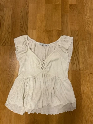 Vit volangblus med knyt framtill - Söt vit blus med volangdetaljer och knyt framtill. 