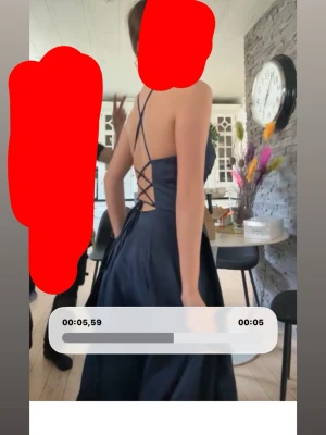 Marinblå långklänning med snörning - Säljer en elegant marinblå långklänning med öppen rygg och snygg snörning i ryggen. Klänningen har smala axelband som korsas och ger en stilren look. Materialet har en lätt glans och faller snyggt. Perfekt för dig som vill sticka ut på bal eller fest. Den är från jj house. Klänningen har ett snitt i höger ben. 