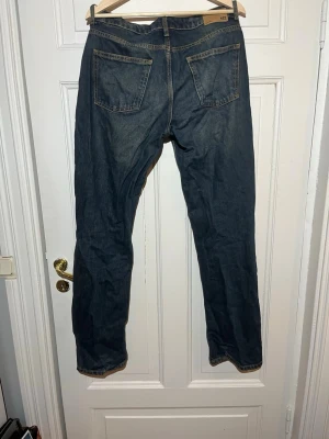 Mörkblå raka jeans från 157 - Säljer ett par mörkblå jeans från 157 med rak passform och klassisk femficksdesign. Jeansen har kontrastsömmar och knappgylf. Perfekta till en avslappnad stil och funkar året runt. Materialet är denim i bomull.