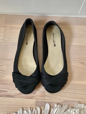Svarta ballerinaskor med twistdetalj - Säljer ett par svarta ballerinaskor. Skorna har en snygg twistdetalj framtill och rundad tå. Höger sko är också en storlek större än den vänstra. OBS: Höger: storlek US7/EU37-38 Vänster: US6/EU36-37. ✨🌸