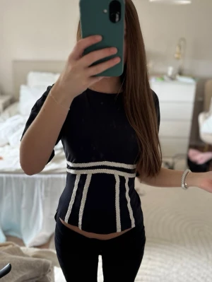 Svarttopp med vita detaljer och öppen rygg - Trendig svart topp med vita detaljer och öppen rygg. Endast använd 1 gång!! Storlek XXS 💐
