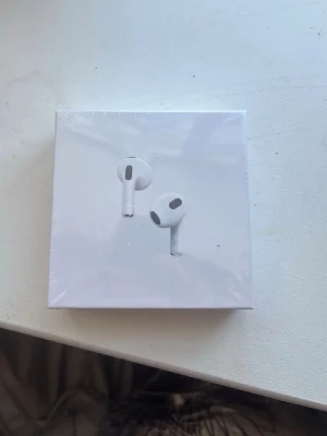 Apple AirPods 3 trådlösa hörlurar - Säljer ett par vita Apple AirPods 3 i originalförpackning. De har en stilren och minimalistisk design med rundade former och sitter bekvämt i öronen. Perfekta för musik, poddar och samtal med grym ljudkvalitet och smidig anslutning till iPhone. Skriv till mig innan ni köper för att de kanske är sålda