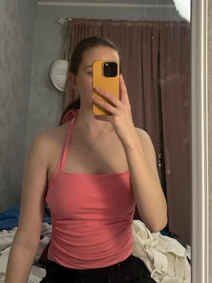 Rosa halterneck topp med knyt - Säljer en rosa halterneck topp med knyt i nacken. Toppen är tight och croppad, perfekt för sommaren. Materialet känns mjukt och stretchigt, 95% bomull. Enkel och snygg design utan mönster.