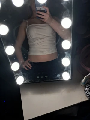 Beige croppad linnetopp - Säljer en beige croppad linnetopp med smala axelband. Toppen har en enkel och stilren design som passar perfekt till jeans eller kjol. Materialet känns mjukt och följsamt mot huden och toppen har en tight passform.