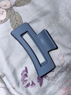 Blå hårklämma i matt plast - Stilren hårklämma i matt blå plast med rektangulär form och öppen mitt. Perfekt för att snabbt sätta upp håret i en trendig look. Klämman har en modern design och passar till många olika frisyrer.