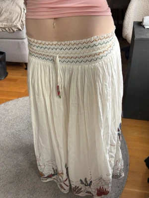 Långkjol  - Säljer en vit långkjol med broderade detaljer i flera färger längst ner! Perfekt inför sommaren💗 Priset är diskuterbart vid snabb affär🥰 