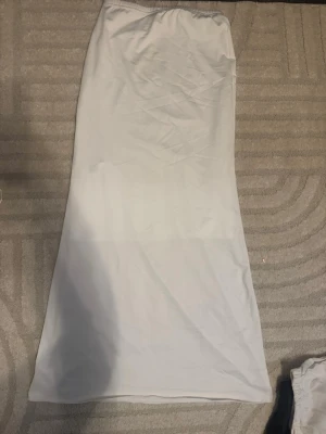 Vit långkjol med enkel design - Säljer en stilren vit långkjol med rak passform och resår i midjan. Kjolen är enkel och passar perfekt till många olika outfits. Det finns en underkjol så den inte e genomskinlig däruppe. Aldrig använd och köpt för 100kr