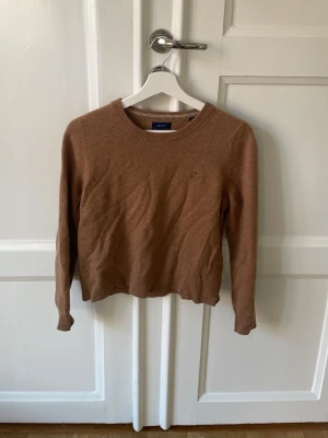 Brun stickad tröja från Gant - Snygg brun stickad tröja från Gant i superfin lammull. Endast använd ett fåtal gånger. Storlek M men passar även S. 