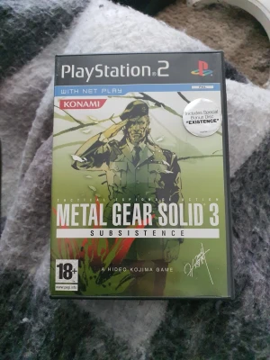 Playstation 2 spel  - Metal Gear Solid 3 Subsistence till PlayStation 2. Omslaget är grönt med en illustration av Snake och spelet är märkt med 18+. Inkluderar specialutgåva med bonusdisc 'Existence'. Perfekt för dig som gillar taktiska actionspel.