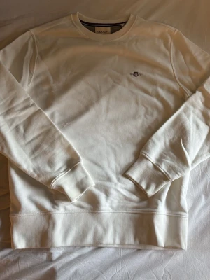 Vit sweatshirt från GANT M - Klassisk vit sweatshirt från GANT med rund halsringning och broderad logga på bröstet. Är 190 80kg och tröjan passar bra. Använd en gång.