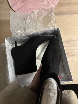 Svarta spetsiga stövletter i mocka - Säljer ett par svarta stövletter med squaretoe och smal låg klack. Skorna är i mjuk mocka och har en stilren design. Perfekta för dig som gillar trendiga boots med lite edge.