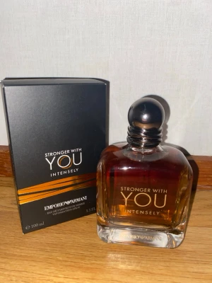 Emporio Armani Stronger With You Intensely 100ml - Stronger With You Intensely från Emporio Armani är en herrparfym i en stilren, mörkbrun glasflaska med svart rund kork. Förpackningen är svart med eleganta guldlinjer och vit text. Flaskan innehåller 100 ml Eau de Parfum.