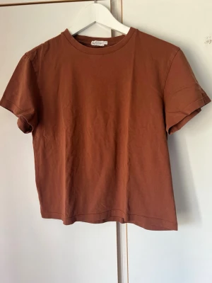 Brun basic t-shirt i bomull - En enkel brun t-shirt  i mjuk bomull. Modellen har rund halsringning och korta ärmar, perfekt för en avslappnad stil. Passformen är normal och tyget känns skönt mot huden. En klassisk t-shirt som funkar till det mesta.