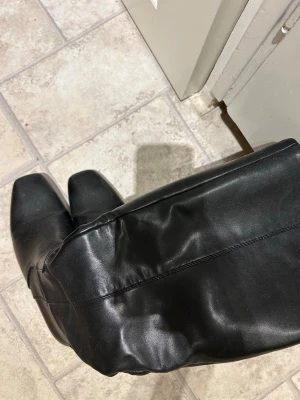 Svarta knähöga stövlar med klack - Säljer ett par svarta knähöga stövlar i skinnimitation med fyrkantig tå och smal klack. Dragkedja på insidan för enkel påtagning. Snygg och stilren design som passar till många outfits. Storlek 38, inga defekter! Använda max 5 gånger. Ifrån na-kd. 🩷