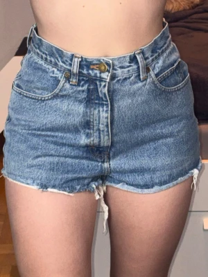 Högmidjade jeansshorts från Eddie Bauer Denim  - Klassiska blå jeansshorts från Eddie Bauer Denim med hög midja och fransiga benslut. Shortsen har fem fickor, bälteshällor och knappgylf. Perfekta för varma dagar och ger en avslappnad vintagekänsla.💙