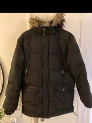 Svart dunjacka från bondelid - Jackan har två stora fickor med knappar, två vedragkedjefickor och quiltad design. Perfekt för kalla vinterdagar. Använd 2 gånger 