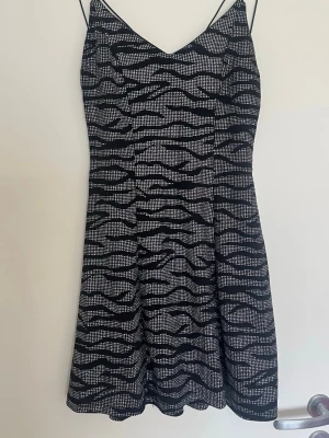 Svartvit zebramönstrad kort klänning - Snygg kort klänning med zebramönster i svart och vitt. Klänningen har tunna axelband och v-ringad hals. Perfekt för dig som vill sticka ut med ett djurmönster och en enkel men trendig siluett.