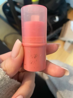 Krämrouge i stick, rosa ton - Säljer ett krämrouge i praktiskt stickformat med en mjuk rosa nyans. Förpackningen är cylinderformad och går i matchande rosa plast. Perfekt för att snabbt fräscha upp kinderna och ge ett naturligt glow. Enkel att ta med i väskan.