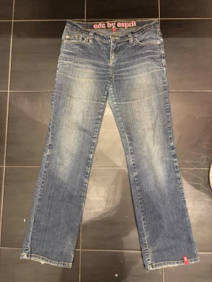 Blå jeans från edc by Esprit - Snygga blå jeans från edc by Esprit med raka ben och klassisk femficksmodell. Jeansen har ljusa slitningar framtill och detaljer i gult på sömmarna. Tillverkade i denim med en cool vintagekänsla. Perfekt om man vill sy om eller ha straight jeans. Jag är 158cm och de nått precis till hälen. PRISET ÄR INTE HUGGET I STEN!!
