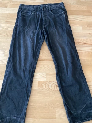 Svara baggy jeans - Säljer ett par svarta jeans från Fjällräven med rak passform och klassisk femficksdesign. Jeansen har en diskret logga på bakfickan och är tillverkade i slitstarkt bomullsmaterial. Perfekta för dig som gillar en enkel och tidlös stil.