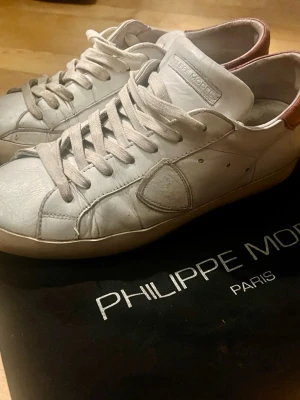 Philippe Model skor - Tja! Säljer dessa äldre par Philippe Model skor för ett otroligt pris. Säljer pågrund av att dem inte passar mig. Dem hade ett föredetta hål under sulan som nu är helt lagat. Skorna är vita med röd baksida. Hör av er vid minsta frågor eller funderingar!