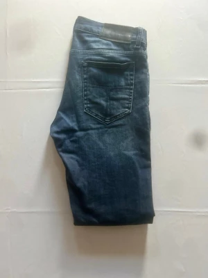 Tiger of sweden jeans - Tiger of Sweden jeans i mörkblå tvätt, storlek W31/L32. Slim fit med modern, smal passform och snygg slitning över lår och knän. Klassisk femficksmodell med låg midja. Mjuk denim med lite stretch som formar sig efter kroppen.