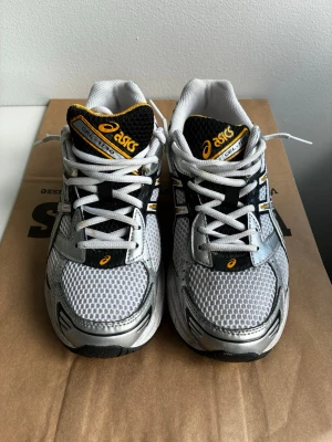 Asics Gel-1130 vita och silver sneakers - Snygga Asics Gel-1130 sneakers i vitt, silver och svart med gula detaljer. Använda, hör av er för frågor 