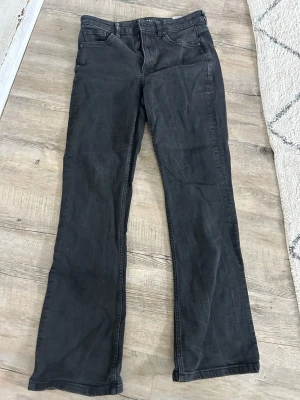 Svarta bootcut jeans  - Säljer ett par svarta bootcut jeans från typ Cubus el Lindex med klassisk dragkedja o knapp. Jeansen har raka ben med lätt utsvängning och är tillverkade i ett mjukt denimtyg. Lite stechiga och heter Sam. 