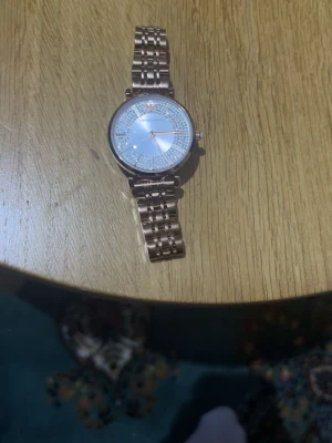Emporio Armani klocka i roséguld - Snygg klocka från Emporio Armani i roséguld med metallarmband. Urtavlan är silverfärgad och dekorerad med glittriga detaljer runt siffrorna. Klassisk och elegant design som verkligen sticker ut.