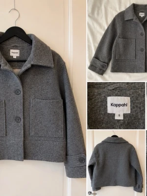 Grå overshirt från Kappahl - Stilren grå overshirt från Kappahl i ullmix. Modellen är boxig med stora framfickor, bred krage och knäppning med stora knappar. Ärmsluten har dekorativ knappdetalj. Perfekt lager-på-lager-plagg för en trendig look.