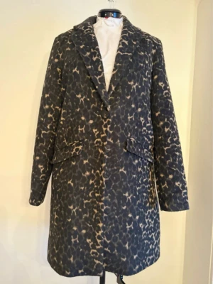 Leopardmönstrad rock med knappar - Snygg rock med leopardmönster i svart och beige. Klassisk rak passform med slag, två framfickor med lock och knäppning framtill. Perfekt statement-plagg för dig som vill sticka ut. Tjockare material som passar bra till kyligare dagar. ⚠️🐶🐕 har hundar hemma, så kappan kan innehålla spår av hårstrån.. 