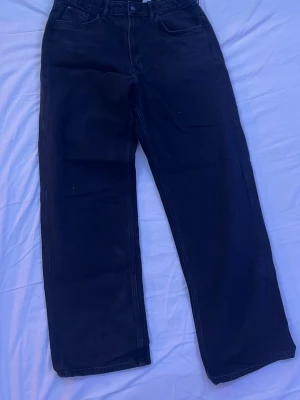 Svarta raka jeans - Säljer ett par svarta jeans med rak passform och klassisk femficksdesign. Jeansen har hög midja och är tillverkade i ett kraftigare denimtyg. Perfekta för dig som gillar en enkel och stilren look.