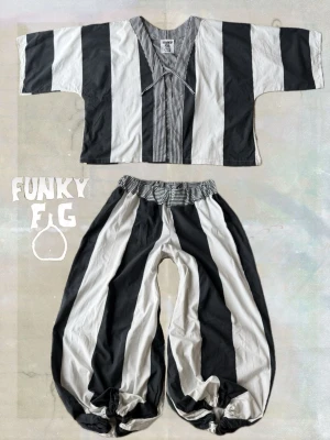 Randigt set från Funky Fig - Återbruk i sin bästa form ! Unikt set från Funky Fig med breda svart-vita ränder. Toppen har V-ringning och vida ärmar. Byxorna är löst sittande med resår i midjan och vid benslut. Tillverkat av gamla lakan i bomull. Sitter såhär på mig med storlek 40.  Pris: 1650 :-  🍄 Funky Fig 🍄  Återbrukade material, nytt liv och småskaligt hantverk. Tack för ditt stöd! Get funky! ✨