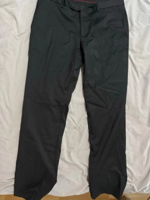 Svarta kostymbyxor med rak passform från Dressman - Snygga svarta kostymbyxor med rak passform och klassisk design. Byxorna har bälteshällor, knapp och dragkedja fram samt diskreta fickor. Perfekta till skjorta eller kavaj för en clean look.