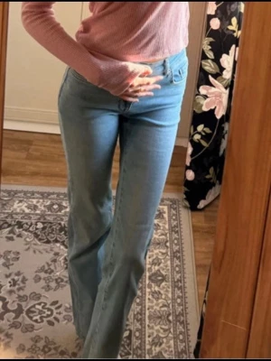 Ljusblå raka jeans med mellanhög midja  - Säljer ett par ljusblå jeans med rak passform och mellanhög midja. Jeansen har klassiska fickor och stängs med dragkedja och knapp. Perfekta till vardags och lätta att matcha med olika toppar