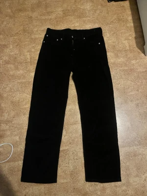 Svarta Levi's manchesterbyxor - Svarta manchesterbyxor från Levi's med klassisk fyrficksdesign och raka ben. Byxorna har en tydlig struktur i tyget och en läderpatch med Levi's-logga bak i midjan. Perfekta för dig som gillar en tidlös och stilren look.