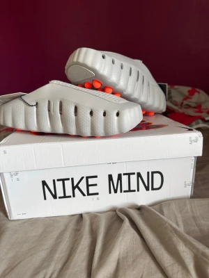 Nike Mind 001 HQ4307-003 – Helt nya/Oanvända – EU 42  - Nike Mind 001 HQ4307-003 i storlek EU 42 (26,5 cm). Helt nya och oanvända med originalkartong. Modern och unik modell från Nike med innovativ design och mycket hög komfort. Färg: Light Smoke Grey/Photon Dust/Hyper Crimson/Chrome. Perfekta för vardag, återhämtning eller för dig som samlar på ovanliga Nike-modeller. Säljs på grund av att de inte används. Kan skickas eller hämtas. Hör gärna av dig vid frågor eller för fler bilder.