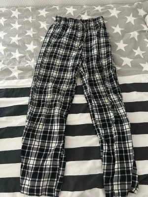 Rutiga pyjamasbyxor svartvit - Säljer ett par klassiska pyjamasbyxor i svartvitt rutigt mönster. Byxorna har resår i midjan för extra komfort och är tillverkade i ett mjukt och lätt tyg. Jag är 163 cm och dem passar mig bra i längden