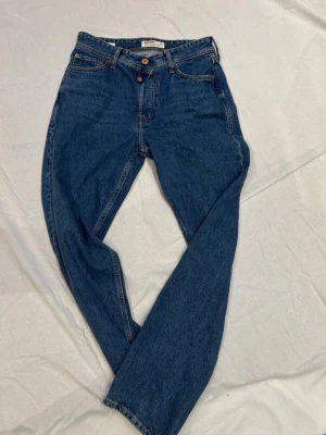 Blå loose fit jeans från Jack & Jones - Säljer ett par klassiska blå jeans från Jack & Jones i loose fit-modell. Jeansen har fem fickor, raka ben och är tillverkade i slitstark denim. Perfekta för en avslappnad och trendig look.