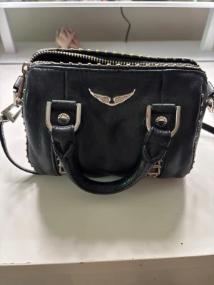 Zadig & voltaire väska - Väskan är äkta, den har dock rostat på vissa ställen vilket gör att jag säljer den mycket billigt. Skicket är bra och den har inte gått sönder någonstans. 