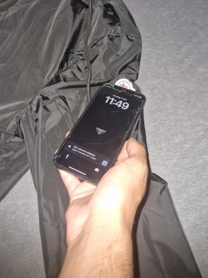 Svart Moncler vindjacka med huva - Snygg svart vindjacka från Moncler med dragkedja framtill och två fickor med knappstängning. Jackan har huva med vit och röd kant samt Moncler-logga på ärmen. Perfekt för blåsiga dagar och enkel att matcha till olika outfits.