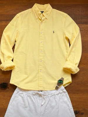 Ralph Lauren Skjorta Herr Smal Slim Fit Gul  - Snygg och klassisk Polo Ralph Lauren Oxfordskjorta i ljusgul färg. Perfekt vår- och sommarskjorta som sticker ut lagom mycket samtidigt som den behåller den klassiska Ralph Lauren-stilen. Den ljusa gula färgen fungerar väldigt bra tillsammans med vita shorts eller beige chinos.                                                      Kommer från ett rökfritt hem.                            Snabb leverans 📦                                    Bundledeals finns.     