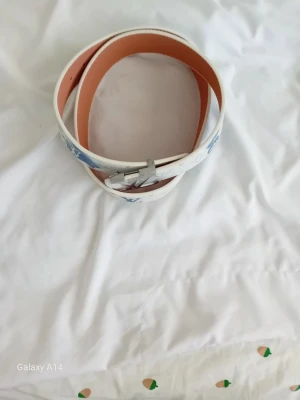 Vitt bälte med silverfärgat spänne - Snyggt vitt bälte med silverfärgat spänne och ljusbrun insida. Bältet har en stilren design och är tillverkat i skinn. Perfekt accessoar för att lyfta din outfit.
