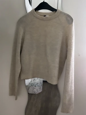 Beige stickad tröja från H&M Divided - Mysig beige stickad tröja från H&M Divided med rund halsringning och långa ärmar. Tröjan har ribbade muddar vid ärmslut och nederkant, och är tillverkad i ett mjukt material som passar perfekt till höst och vinter.