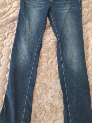 True Religion Billie Mid Rise Jeans - Säljer ett par blå jeans från True Religion, modell Billie Mid Rise Straight. Jeansen har raka ben och klassisk femficksdesign. Materialet är denim med snygga slitningar och kontrastsömmar. Perfekt för dig som gillar en tidlös och cool look.