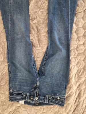 Blå True Religion Joey flare jeans - Säljer ett par blå True Religion Joey Low Rise Flare jeans med klassiska kontrastsömmar och låg midja. Jeansen har utsvängda ben och femficksmodell. Perfekta för dig som gillar en avslappnad men trendig look.